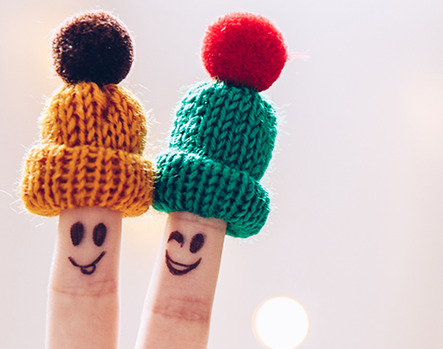 Reducing Stress Funny couple fingers on knitted winter warm hats smiling and wink