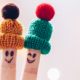 Reducing Stress Funny couple fingers on knitted winter warm hats smiling and wink